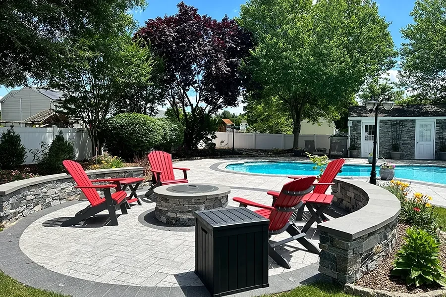 Circular stone fire pit patio beside a swimming pool