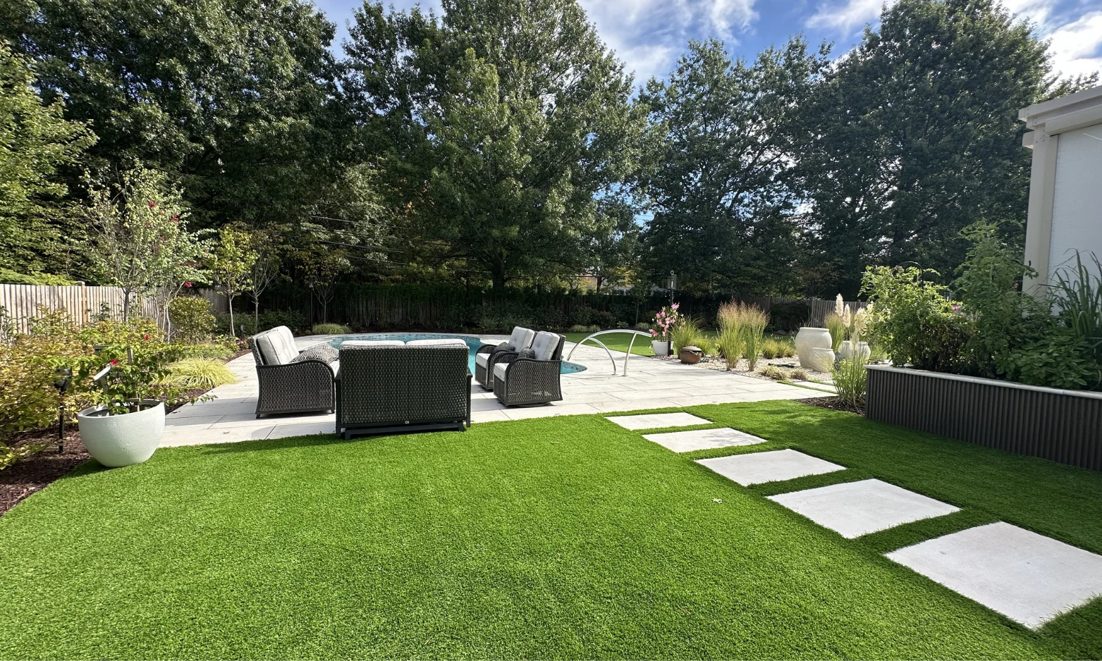 Porcelain patio and lawn with stepping stones beside an outdoor kitchen